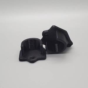May include: Two black plastic 3D printed wall mounts. The mounts have a rounded shape and a flat base.