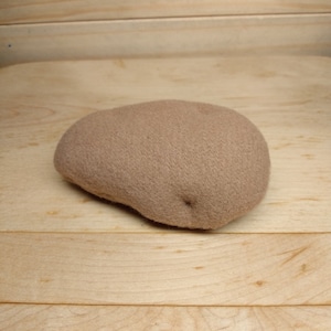 May include: A brown felt potato toy. The potato is soft and plush.