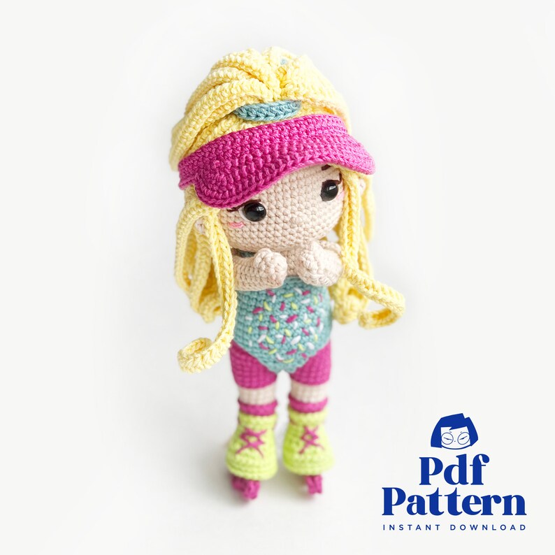 May include: A crocheted doll wearing a pink visor, a turquoise and white patterned leotard, and pink and yellow roller skates. The doll has blonde hair and is holding her hands together in front of her.