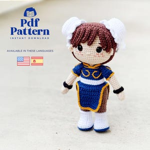 Può includere: Bambola all'uncinetto fatta a mano con un abito blu e giallo, con chignon bianchi. La bambola ha un viso dettagliato con guance rosee e occhi neri. L'immagine include il testo "Pdf Pattern" e "Instant Download".