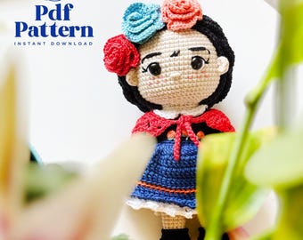 May include: A crocheted doll with a floral headpiece, red shawl, and blue dress. The doll has black hair and is wearing black shoes with orange soles. The image includes the text "Pdf Pattern Instant Download".