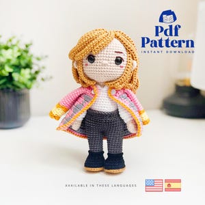 May include: Crochet amigurumi doll pattern in PDF format. The doll has blonde hair, a pink jacket, a white shirt, grey pants, and black shoes. The pattern is available in English and Spanish.  "Pdf Pattern Instant Download"