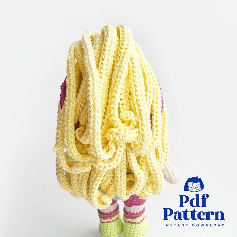 May include: Crochet doll pattern with long yellow hair, pink and white striped dress, and green and white striped shoes. The pattern is available for instant download.