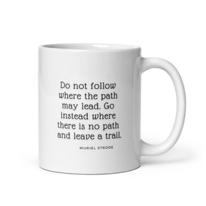 May include: White ceramic mug with a black quote that reads "Do not follow where the path may lead. Go instead where there is no path and leave a trail." The quote is attributed to Muriel Strode.