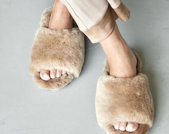 May include: A pair of brown faux fur slippers with a simple, open-toe design. The slippers are made of soft, fluffy material and have a comfortable fit.