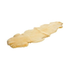May include: A long, cream-colored sheepskin rug with a soft, fluffy texture.