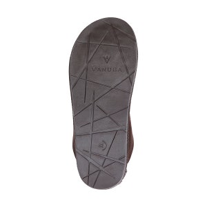 Peut inclure: La semelle d'une chaussure en daim marron avec une semelle en caoutchouc noir. La semelle a un motif g&eacute;om&eacute;trique et le nom de la marque "VANUBA" est imprim&eacute; sur la semelle.