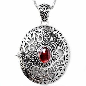Peut inclure: Collier avec médaillon en argent, orné d'un motif complexe et d'une pierre précieuse rouge au centre.