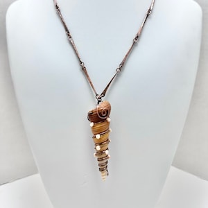 May include: A copper chain necklace with a seashell pendant. The seashell is wrapped in copper wire and has white beads attached.