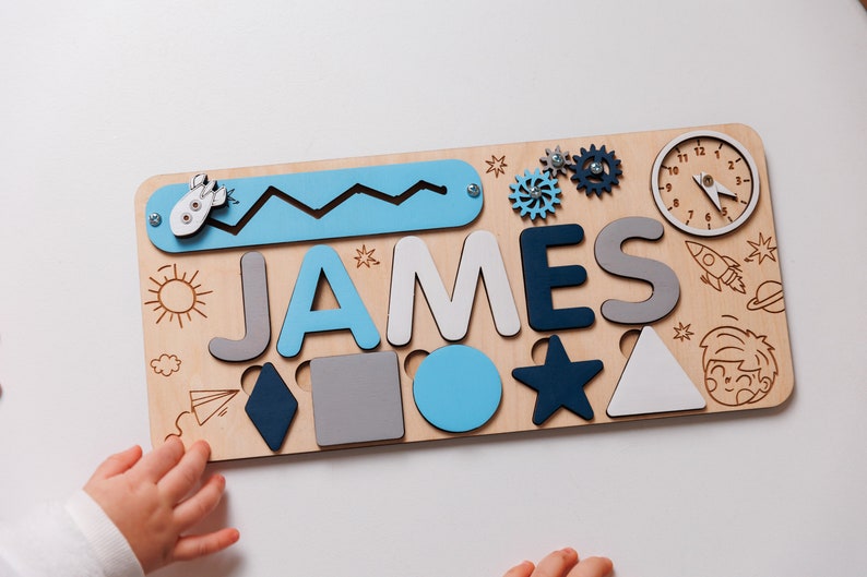 a child's hand holding a wooden name puzzle