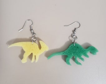 Könnte beinhalten: Ein Paar Ohrringe mit Dinosaurierformen aus gelbem und grünem Schwamm. Die Ohrringe sind an silbernen Haken befestigt.
