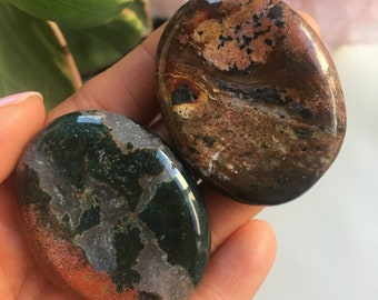 May include: Two polished, oval-shaped stones with a unique, swirling pattern of brown, green, and white. The stones are smooth and have a glossy finish.