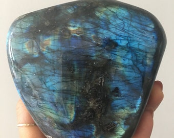 May include: A large, freeform, polished labradorite crystal with a blue, green, and black iridescent sheen.