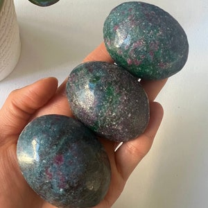 May include: Three smooth, oval-shaped green and pink stones. The stones have a speckled appearance and are polished.