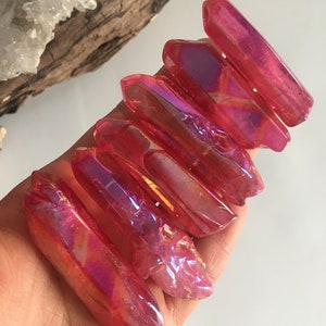 May include: A group of six iridescent pink quartz points. The points are smooth and polished, with a slight shimmer.