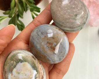 Può includere: Tre pietre lisce, levigate, di forma ovale con motivi a spirale di colore marrone, bianco e grigio. Le pietre sono state levigate e hanno un aspetto naturale e terroso.