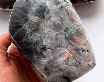 May include: A large, smooth, gray and black labradorite crystal with iridescent rainbow flashes.