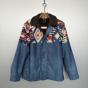 Può includere: Una giacca di jeans blu con un colletto in pelliccia sintetica marrone e un motivo geometrico in stile sud-occidentale sul davanti.