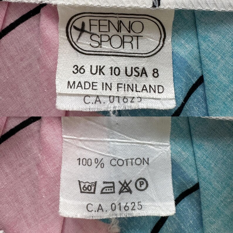 May include: Close-up of two white fabric tags. The top tag reads "FENNO SPORT", size 36 UK 10 USA 8, and "MADE IN FINLAND". The bottom tag reads "100% COTTON" and includes washing instructions. The fabric has pink and blue sections.