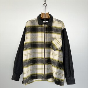 May include: A black and white plaid flannel shirt with a zipper closure and a solid black collar. The sleeves are a solid dark gray color.
