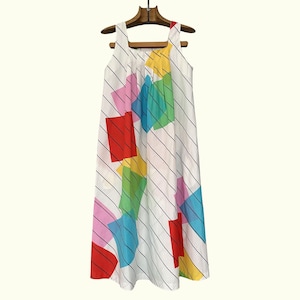May include: A white sleeveless dress with a vibrant geometric design. The dress has a square neckline and is decorated with large, colourful squares and diagonal black stripes. It is displayed on a wooden hanger.