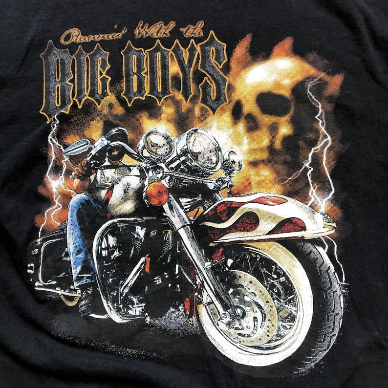 K&ouml;nnte beinhalten: Ein schwarzes T-Shirt mit einem Motiv eines Motorrads mit Flammen und einem Totenkopf. Der Text "Cruised With the Big Boys" ist auf dem T-Shirt aufgedruckt.