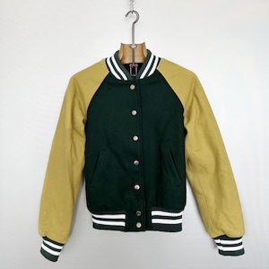 May include: A green and gold varsity jacket with a button-up front. The jacket has gold sleeves and a green body. White stripes accent the collar, cuffs, and hem. The jacket is hanging on a metal hanger.