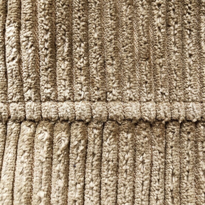May include: Close-up of a brown corduroy fabric with a subtle texture. The fabric has a vertical ribbed pattern and a smooth, soft feel.