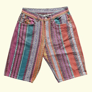 Peut inclure: Short en jean coloré avec un motif à rayures verticales dans les tons de turquoise, rouge, violet et orange. Le short a une conception classique à cinq poches et une fermeture boutonnée. Le motif comprend des motifs géométriques et tribaux.