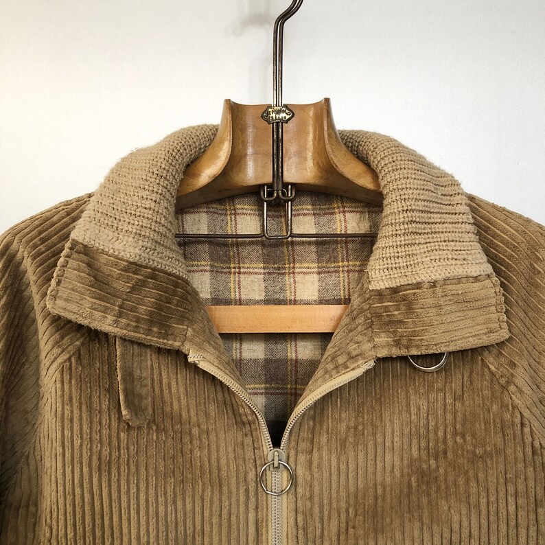 May include: A brown corduroy jacket with a zipper closure and a plaid lining. The jacket has a high collar and a ribbed knit trim.