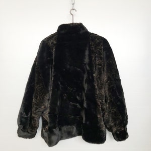 May include: A black faux fur jacket with a leopard print pattern. The jacket has a high collar and a zipper closure.