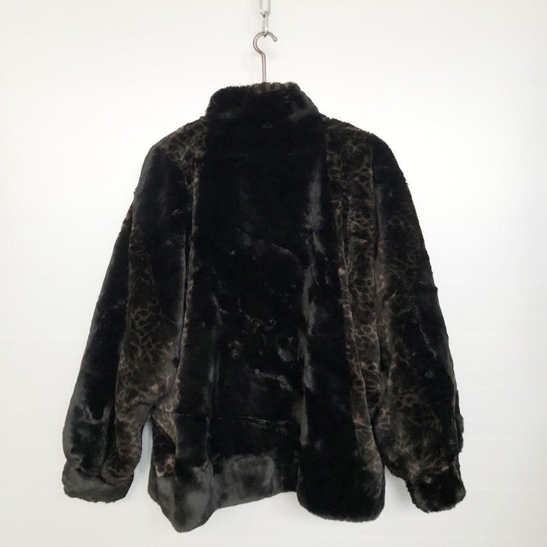 May include: A black faux fur jacket with a leopard print pattern. The jacket has a high collar and a zipper closure.