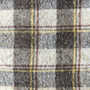 May include: A close-up of a brown and white plaid fabric with a yellow and red woven pattern.