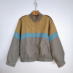 Peut inclure: Une veste bomber bicolore en marron, gris et bleu avec une fermeture éclair.
