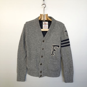 Peut inclure: Chandail gris en tricot avec une lettre F de l'université en bleu marine et blanc et le numéro 7 sur les manches. Le cardigan a un col en V et une fermeture à boutons.