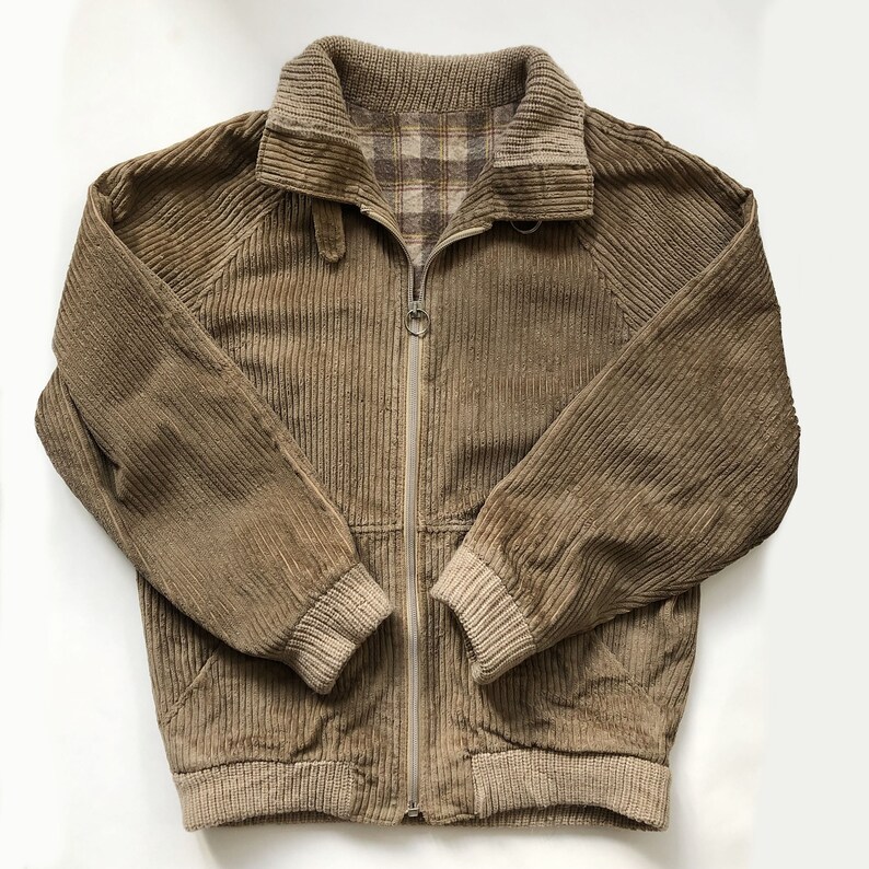 May include: A brown corduroy jacket with a zipper closure and a plaid lining. The jacket has a ribbed collar, cuffs, and hem.
