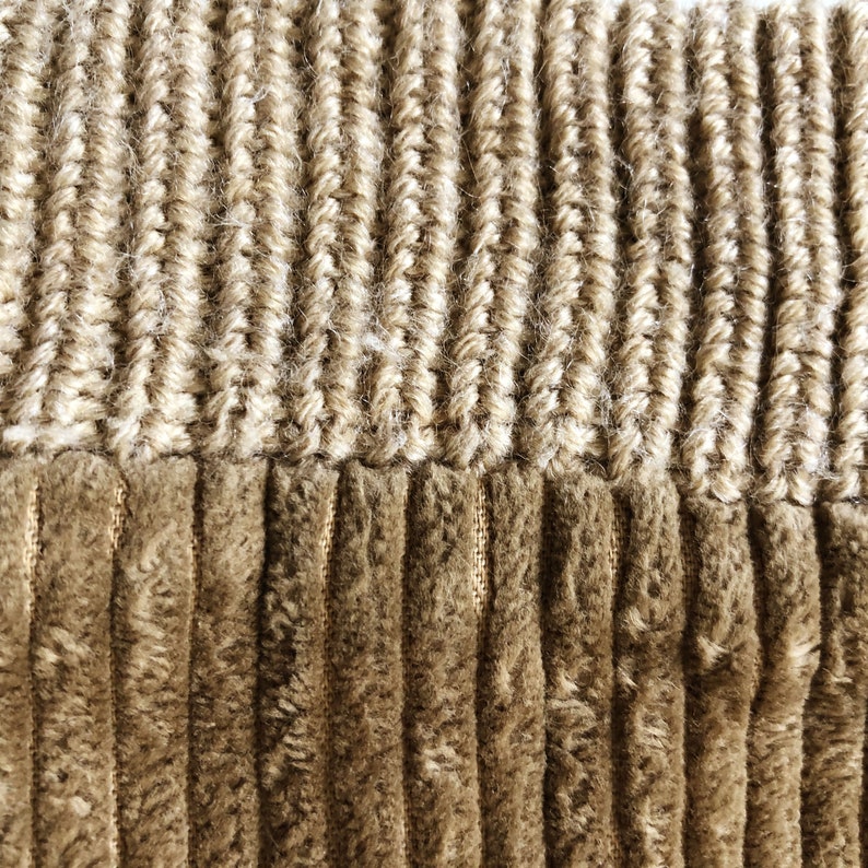 May include: Close-up of a brown corduroy fabric with a beige knit trim. The fabric has a textured, ribbed appearance.