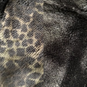 May include: Close-up of a black and brown faux fur fabric with a leopard print pattern.