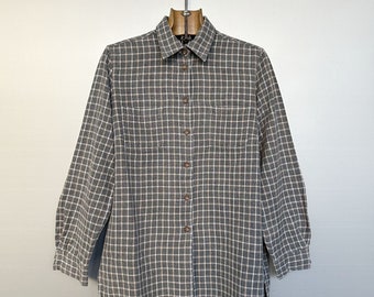 May include: A grey and white checked long-sleeved button-down shirt with two chest pockets.