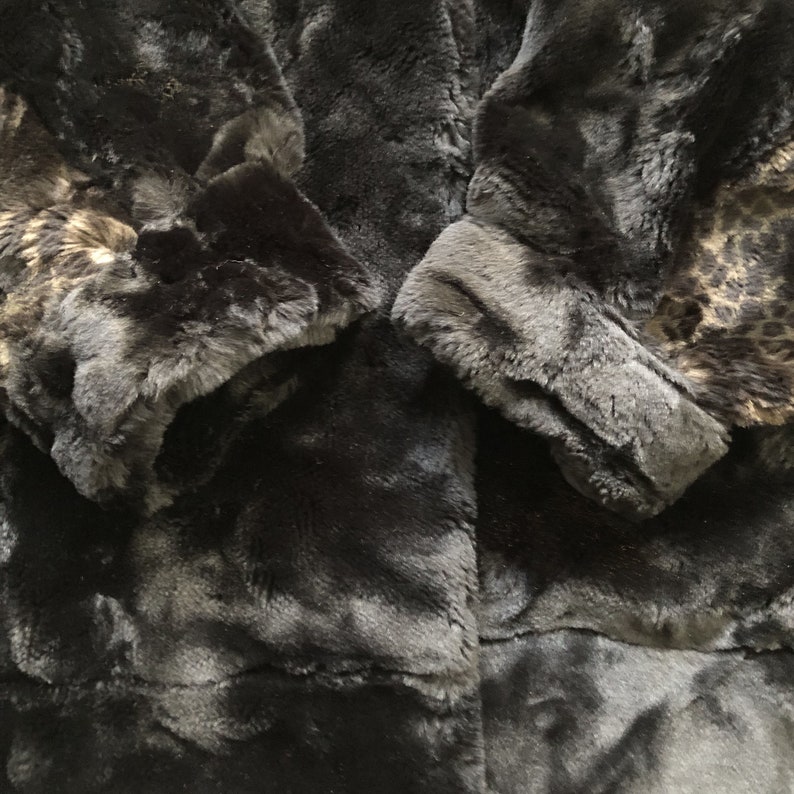 May include: Black faux fur coat with a leopard print lining. The coat has a long sleeve and a soft, plush texture.