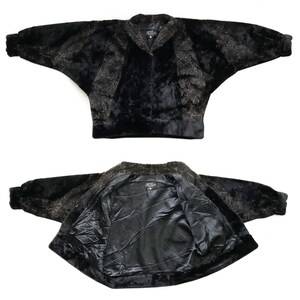 May include: A black and brown faux fur jacket with a leopard print. The jacket has a collar and a zipper closure. The jacket is shown in two views: one with the front of the jacket facing the camera and the other with the inside of the jacket facing the camera.