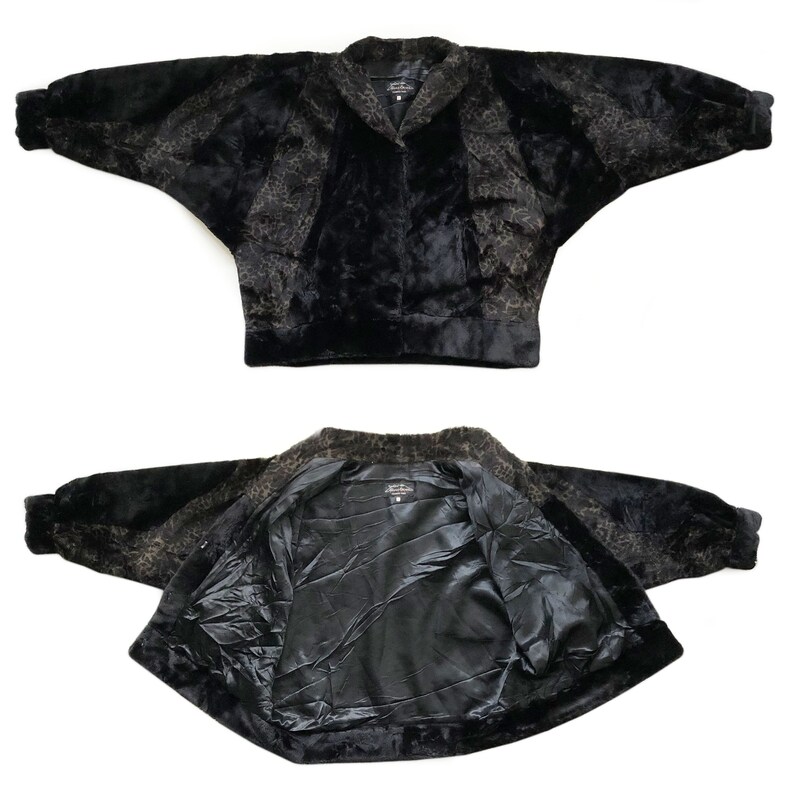 May include: A black and brown faux fur jacket with a leopard print. The jacket has a collar and a zipper closure. The jacket is shown in two views: one with the front of the jacket facing the camera and the other with the inside of the jacket facing the camera.