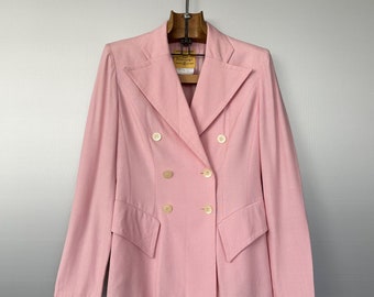 Puede incluir: Una chaqueta rosa de doble botonadura con cuatro botones dorados. La chaqueta tiene un cuello de punta y mangas largas.