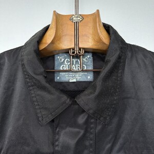 May include: Black jacket with a City Guard label. The label says "Original U.S. style for professional use Gov. order N° 1520-312 Security Protection"