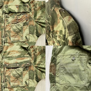 May include: A camouflage jacket with multiple pockets and a zipper closure. The jacket has a green, brown, and tan color scheme. The jacket is made of a durable fabric and has a classic design.