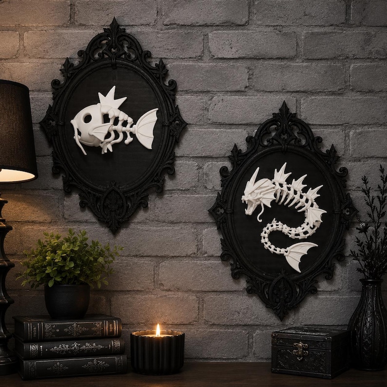 May include: Two oval black ornate frames containing white skeletal fish figures. The left frame features a small fish skeleton, while the right frame displays a larger, serpentine dragon-like fish skeleton. Both are mounted on a gray brick wall.