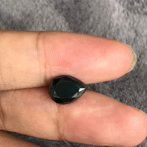 May include: A black pear-shaped gemstone with a faceted cut.