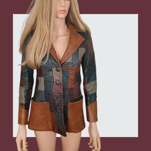 May include: A vintage patchwork leather jacket in shades of brown, green, and black. The jacket has a notched collar, two front pockets, and two buttons. The jacket is displayed on a mannequin.