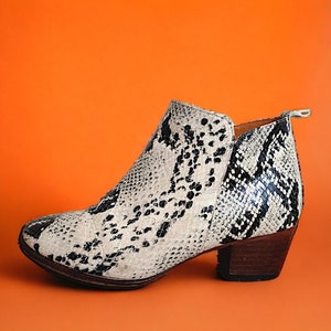 May include: A pair of black and white snake print ankle boots with a block heel.