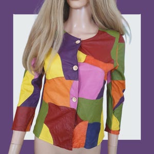 May include: A vibrant patchwork jacket with long sleeves and wooden buttons. The jacket showcases a mix of colours, such as red, yellow, purple, orange, green, and pink. The jacket is made of leather and has a round neckline.